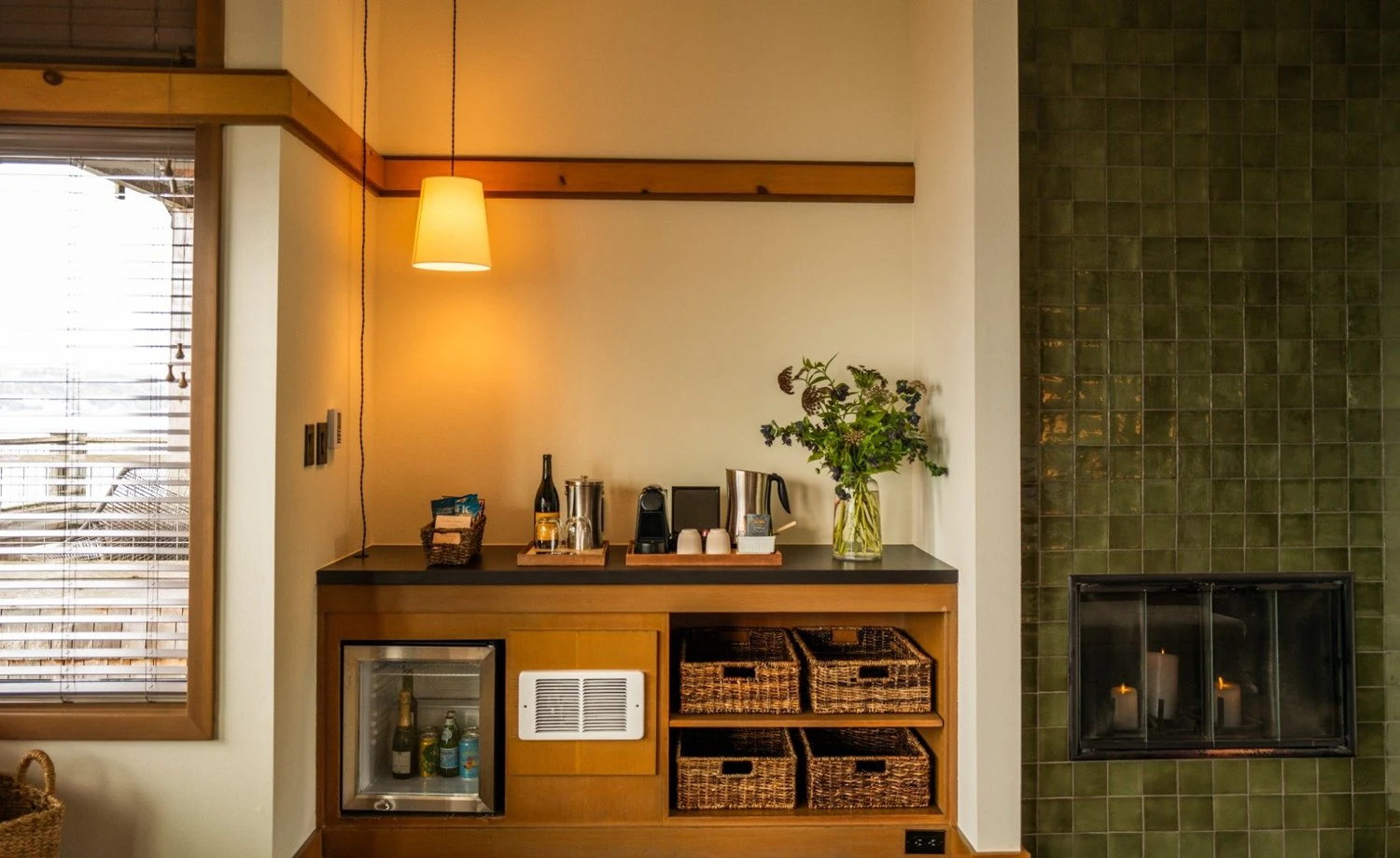 A green tile fireplace and wood minibar with coffee and refreshments in a guest room at The Inn at Langley